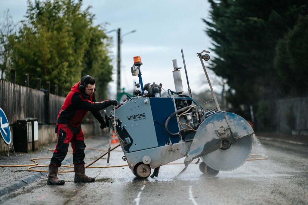 Photo d'une personne entrain de réaliser le sciage béton d'une route
